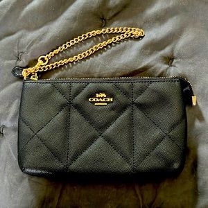 Coach black quilted leather wristlet with card slots inside.